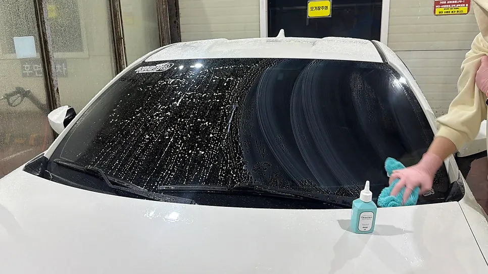 Car glass being treated by rubbing with the dedicated towel