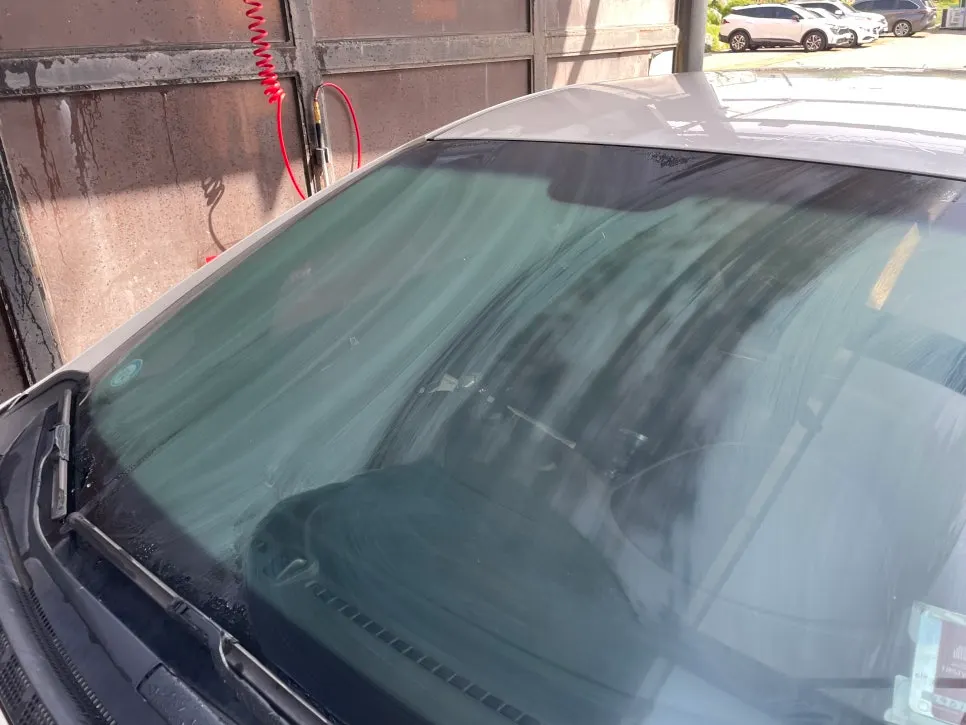 Car glass being wiped while more oil-film remover is applied