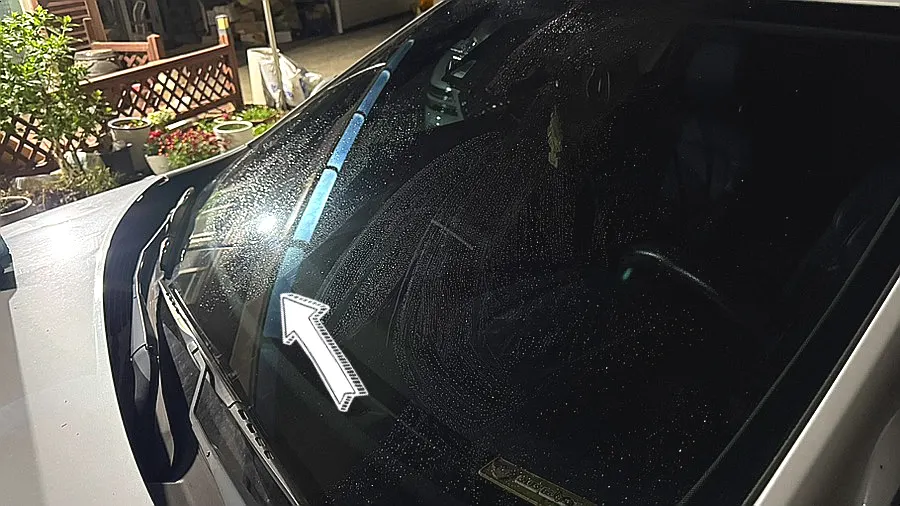 Car glass sprayed with water before treatment in a family home's yard