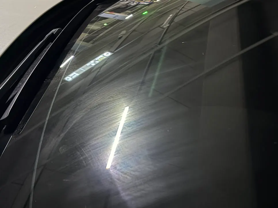 Windshield sprayed with water to check oil film condition