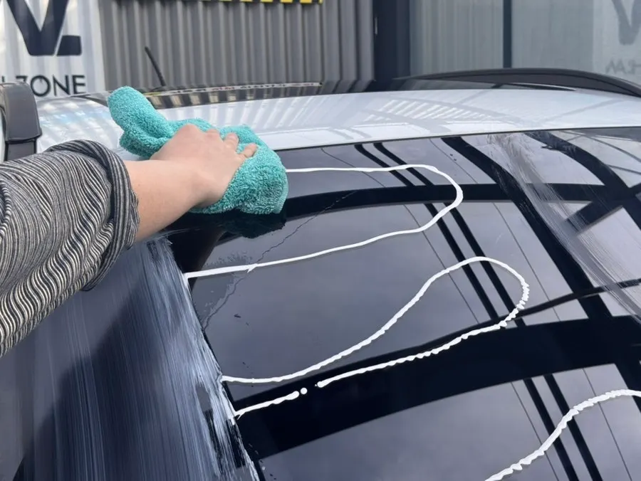 Wiping the windshield with a towel to remove oil film