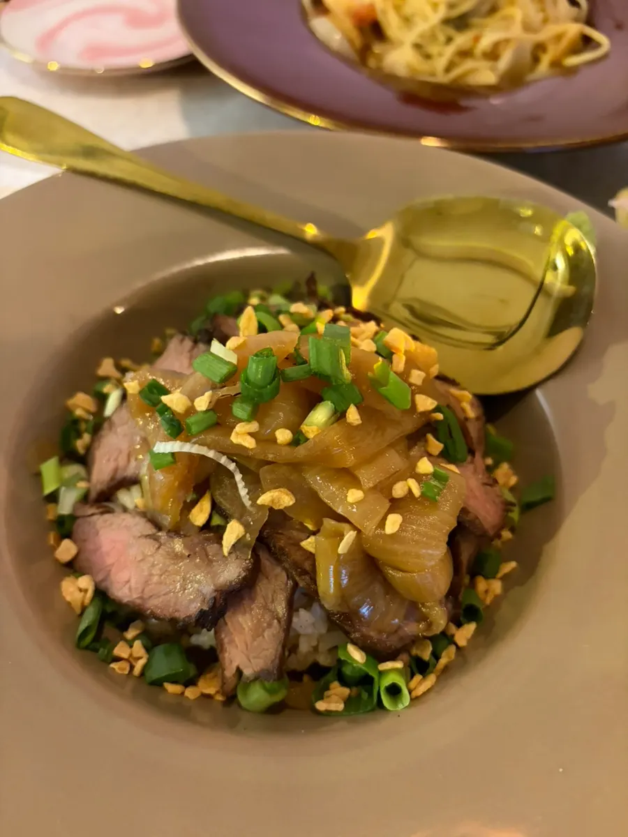 A bite of steak rice bowl topped with wasabi