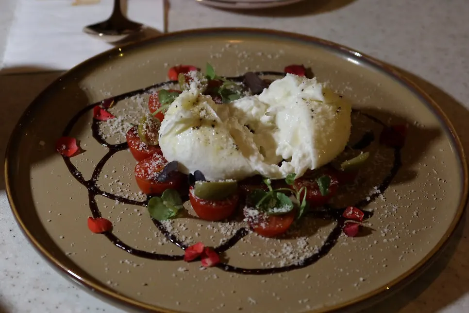 A salad topped with burrata cheese in the center