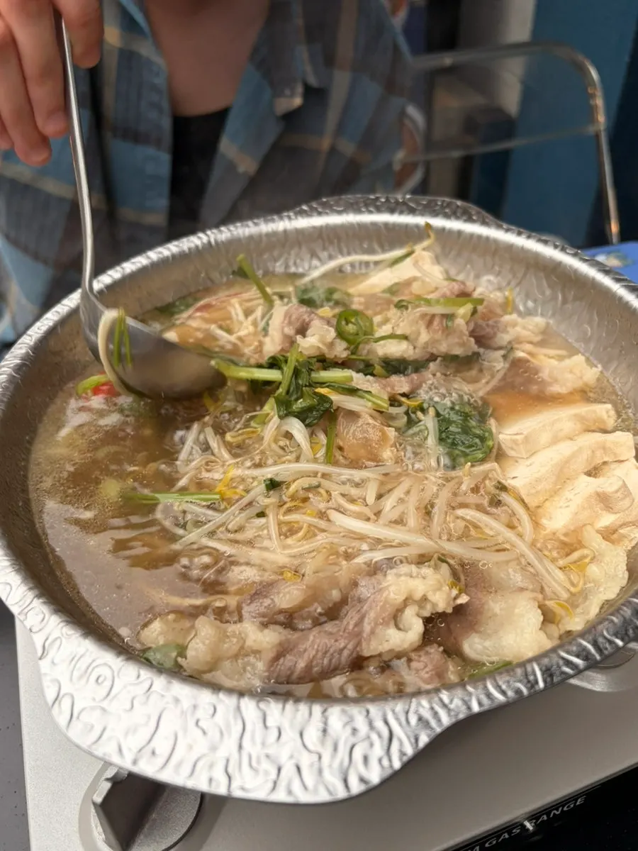 Beef brisket-tendon hot pot topped with minari and bean sprouts