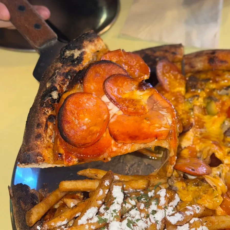 Lifted slice of potato pizza showing its toppings