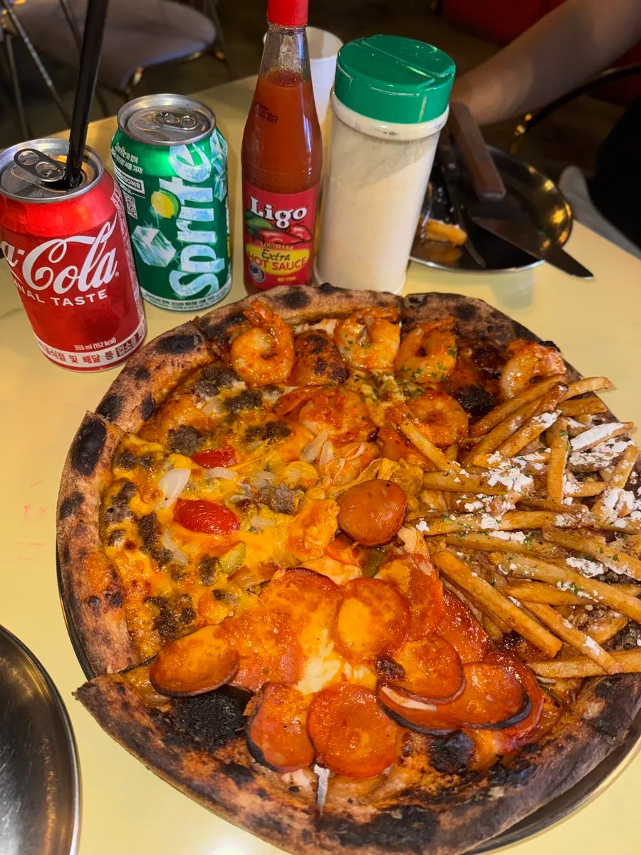 Hot sauce and parmesan cheese powder next to the pizza