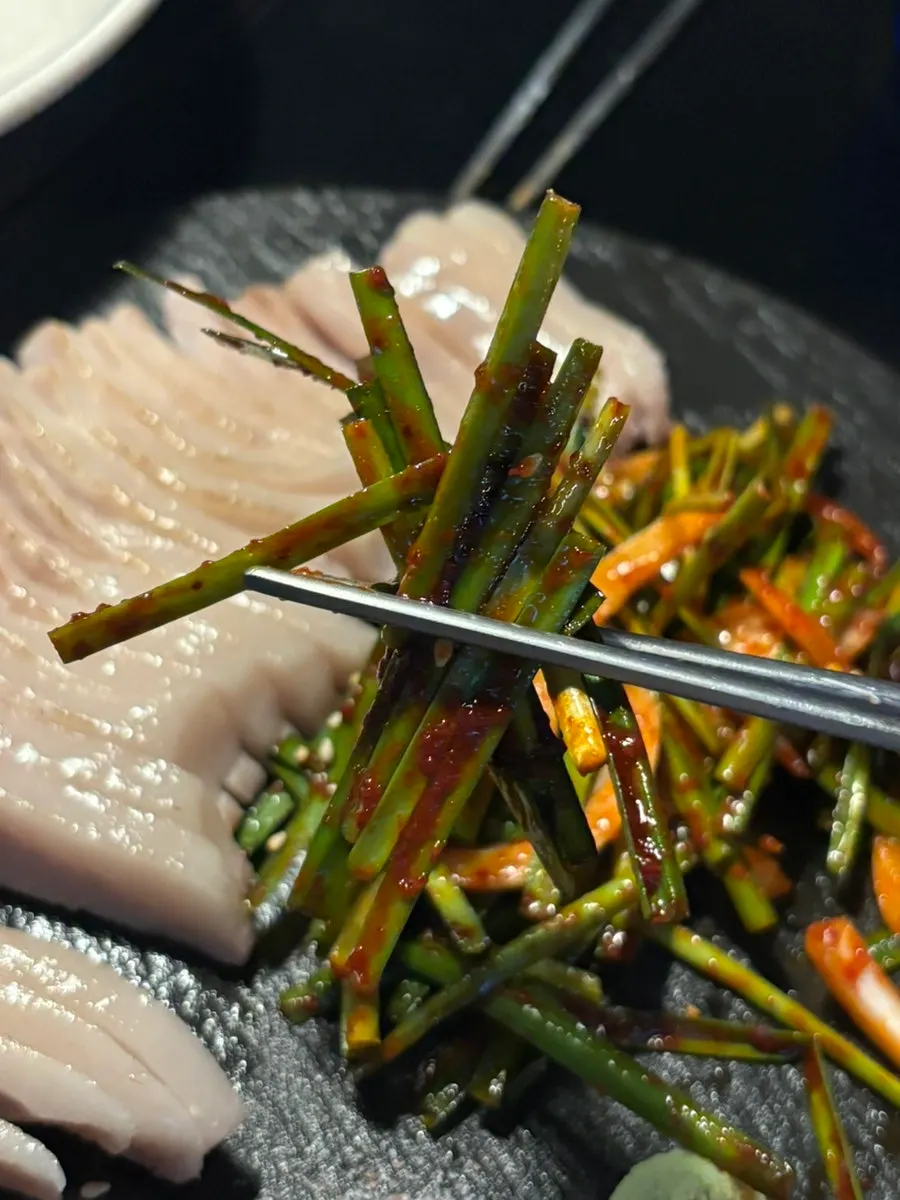 ニラの和え物をのせた豚トロ肉の一切れ
