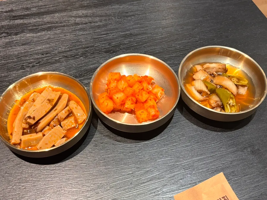 Kkakdugi and pickles served as banchan in brass bowls