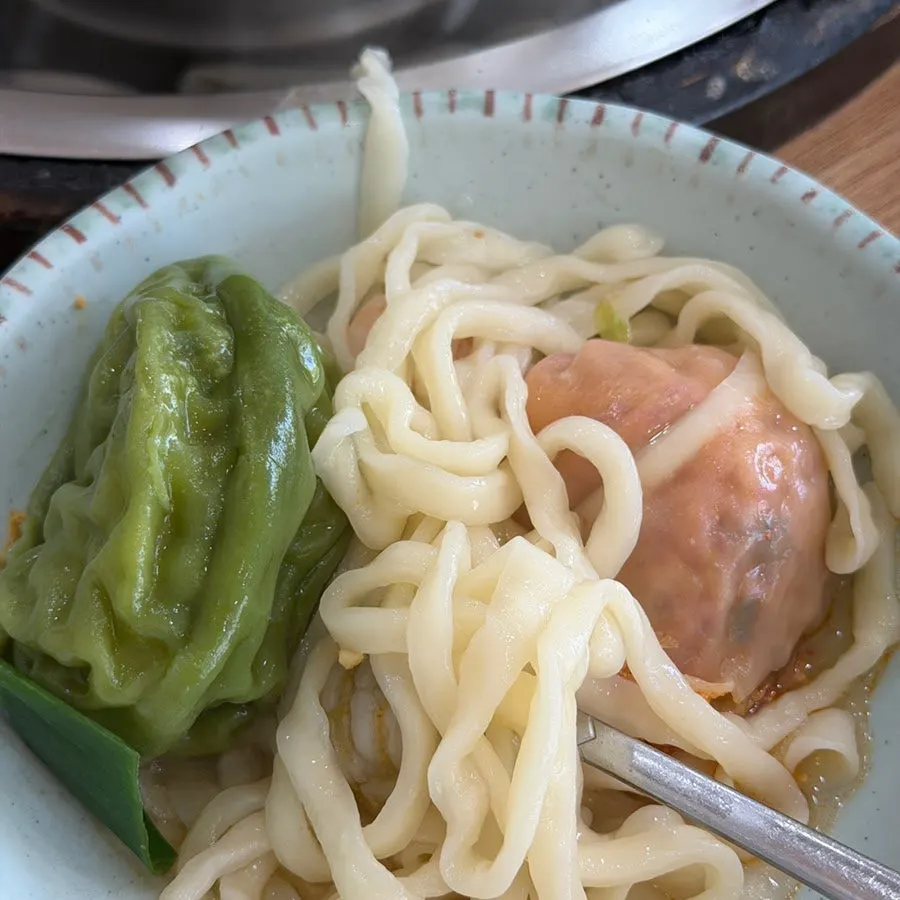 A single wang mandu lifted out with a spoon