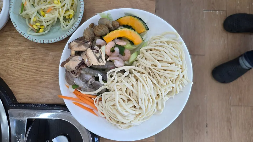 Kalguksu pot topped with shrimp, clams, and sweet pumpkin