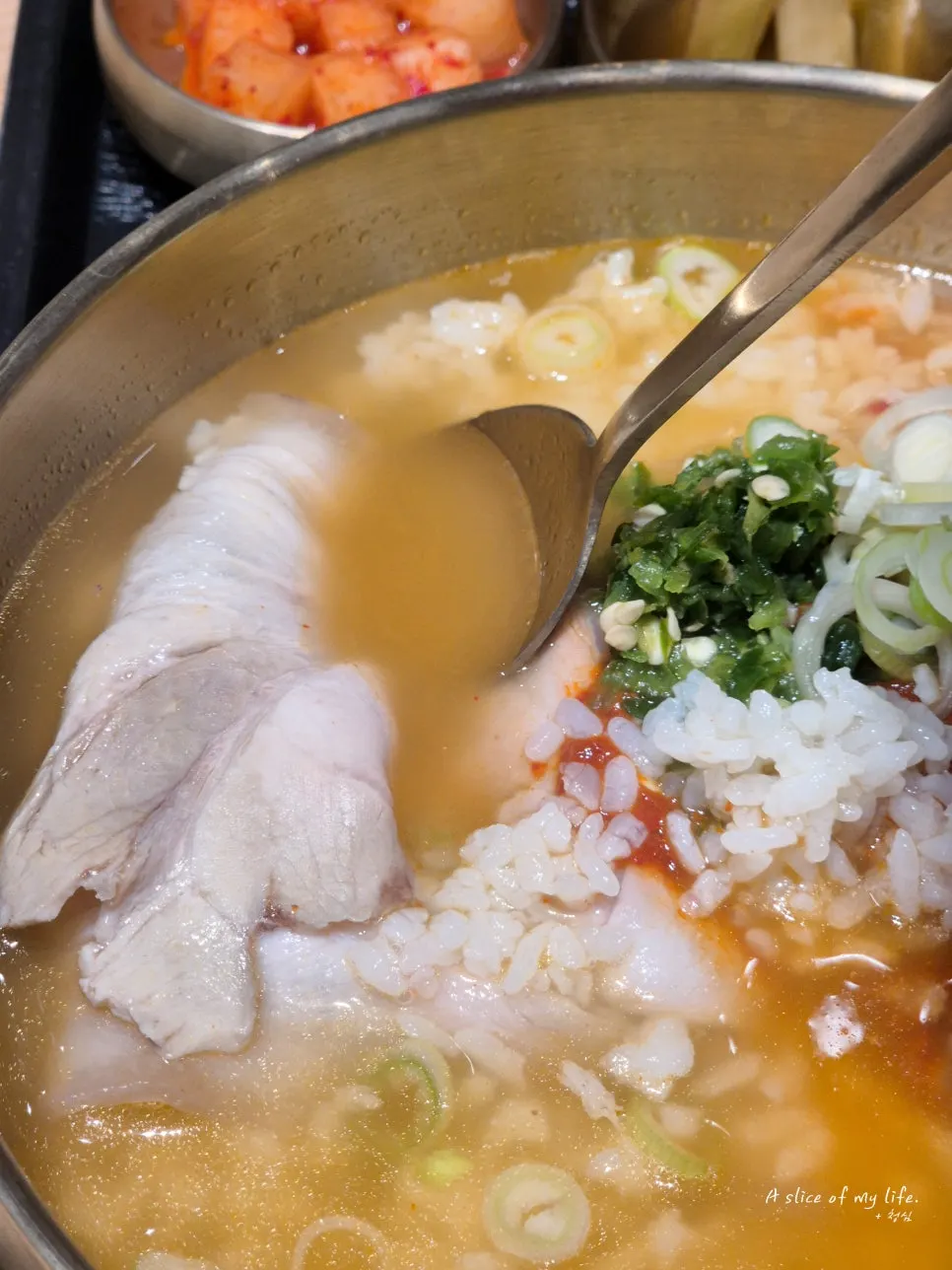 A big chunk of gomtang meat lifted on a spoon