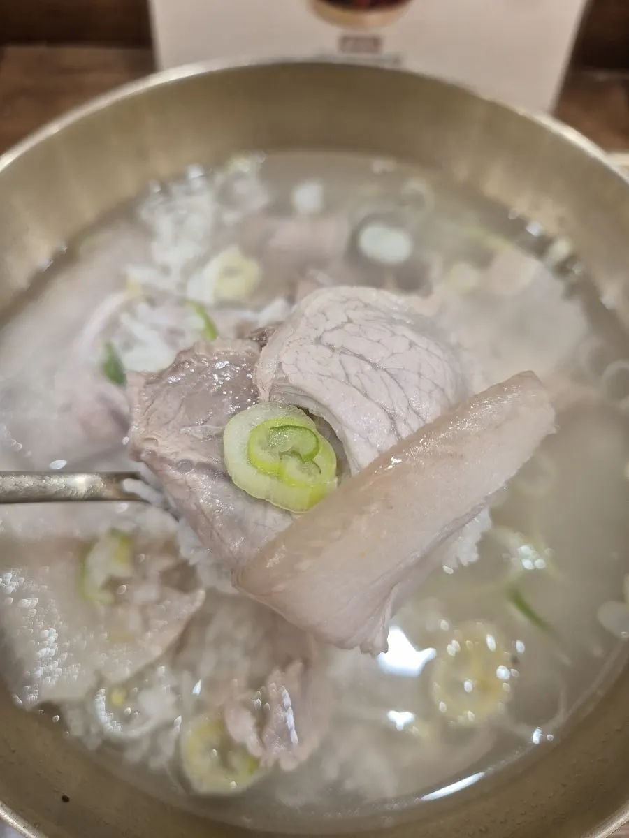 돼지곰탕 속 고기와 밥을 함께 담은 한 술
