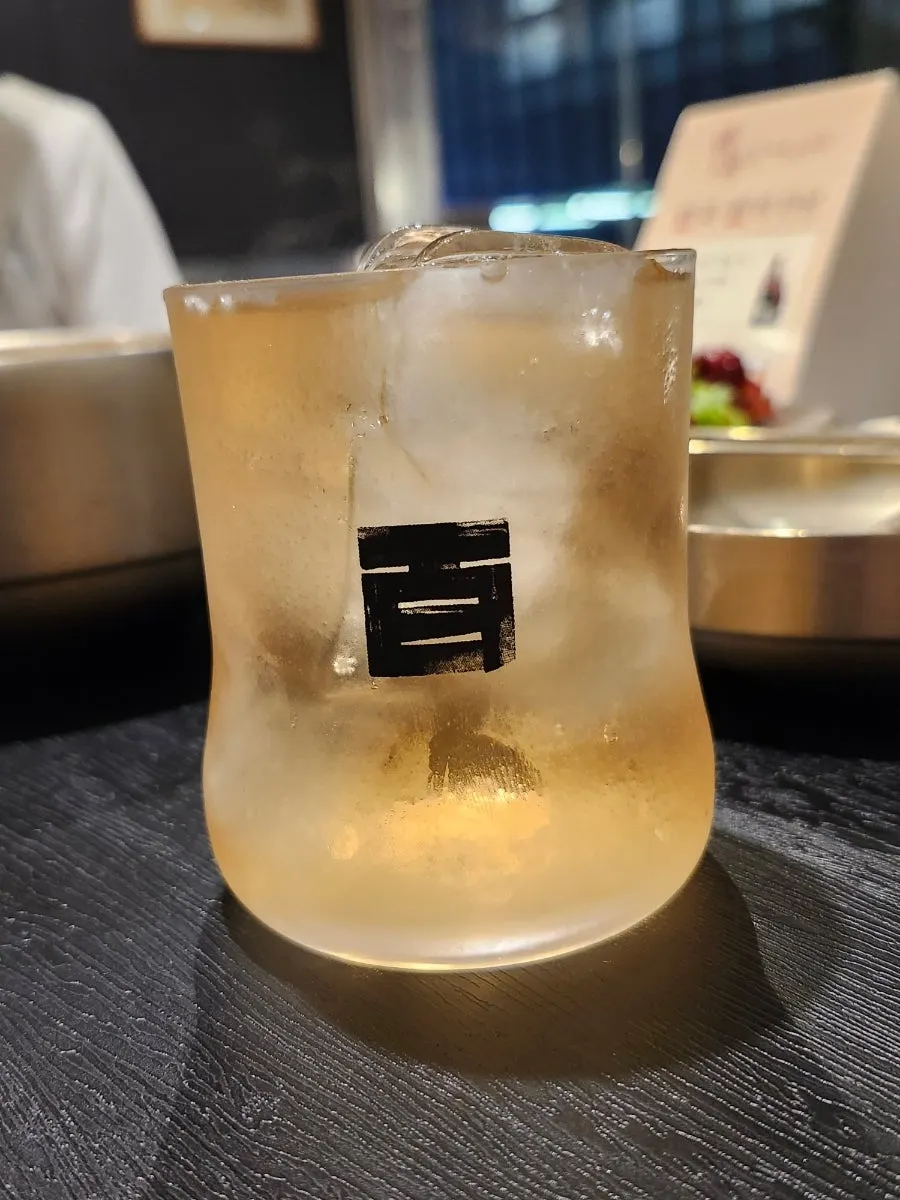 A cool glass of baekseju served with the spicy pig tail