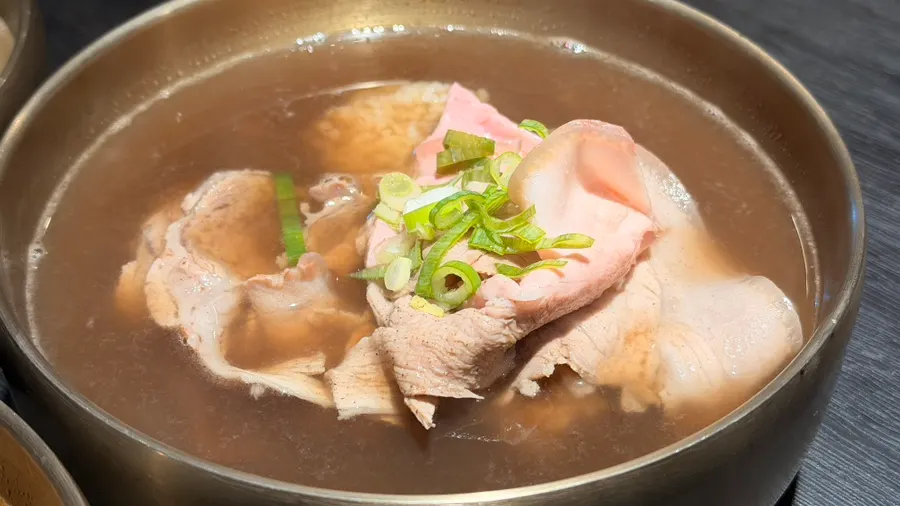A table with gomtang and a glass of traditional rice wine