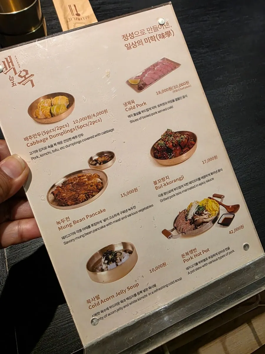 Side menu board listing cabbage mandu, spicy pig tail, and cold boiled pork