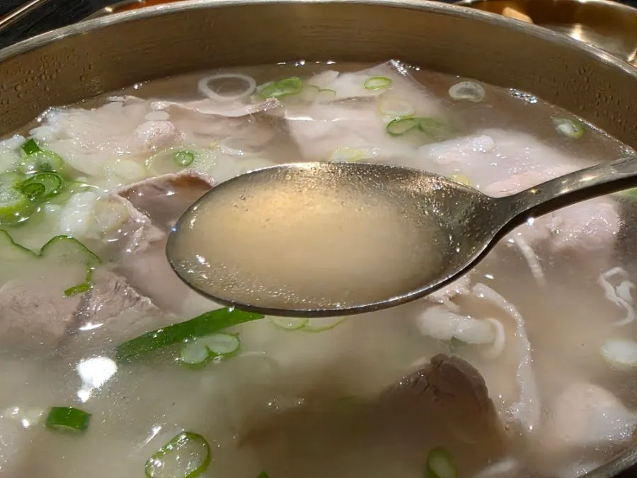 A piece of pork gomtang meat lifted up on chopsticks