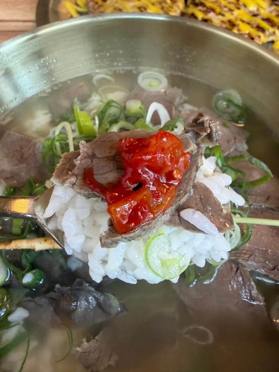 A spoonful of gomtang topped with squid jeotgal