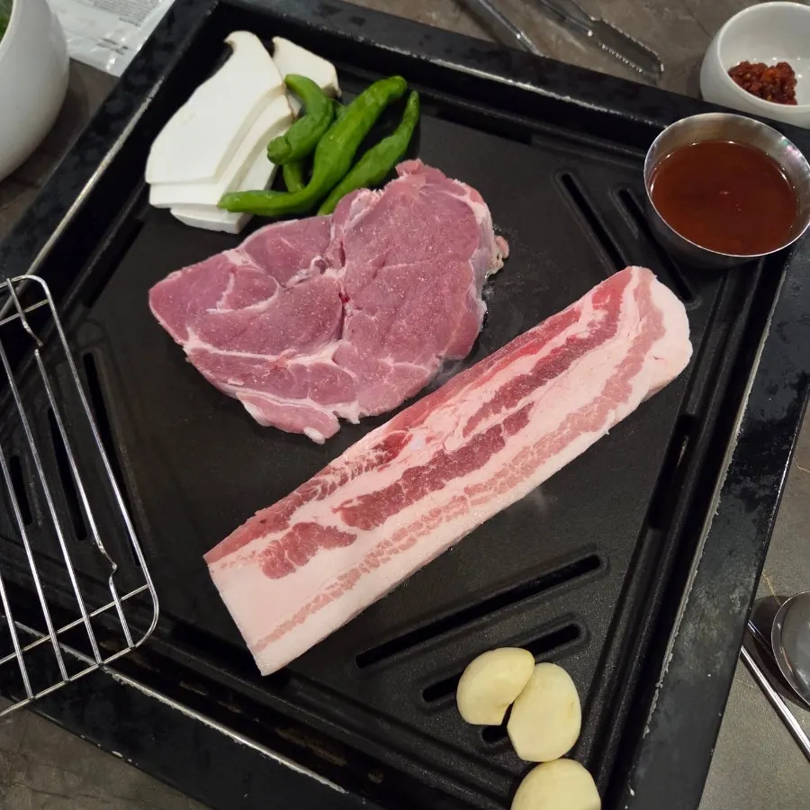 중량 스티커가 붙은 숙성 삼겹살과 목살 한 접시