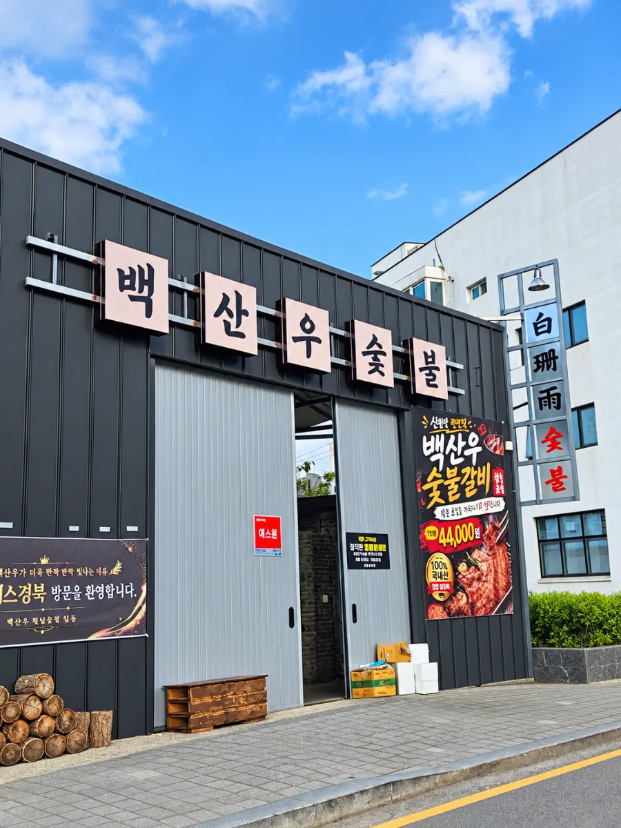 입구 주변에 장작이 쌓인 백산우숯불 외관