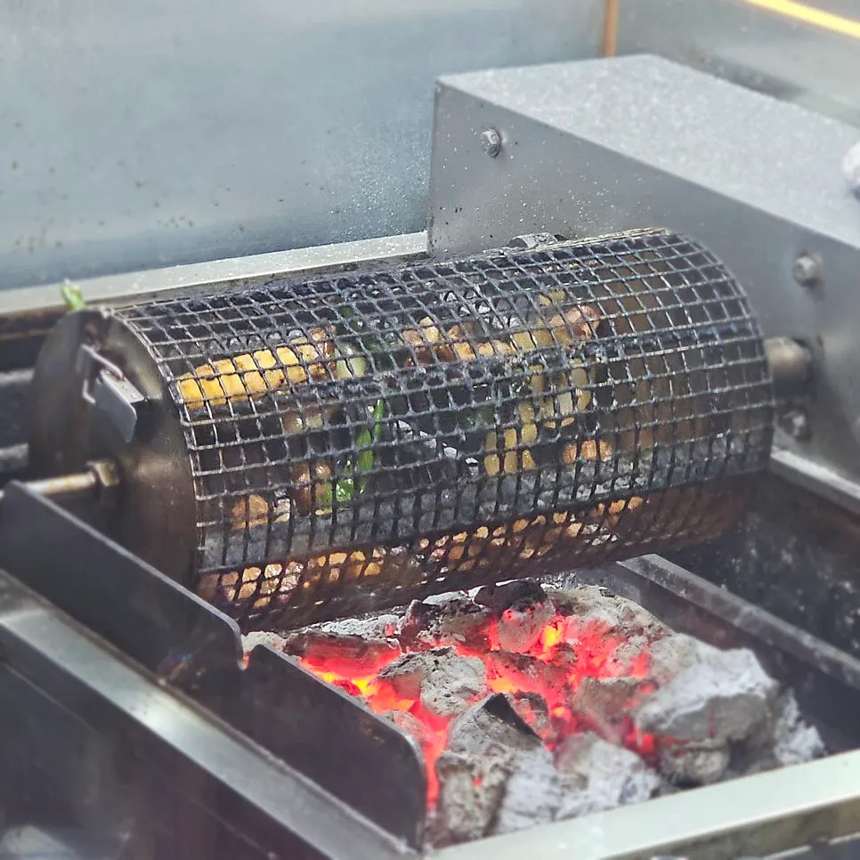 Cylindrical grill spinning over charcoal inside the kitchen
