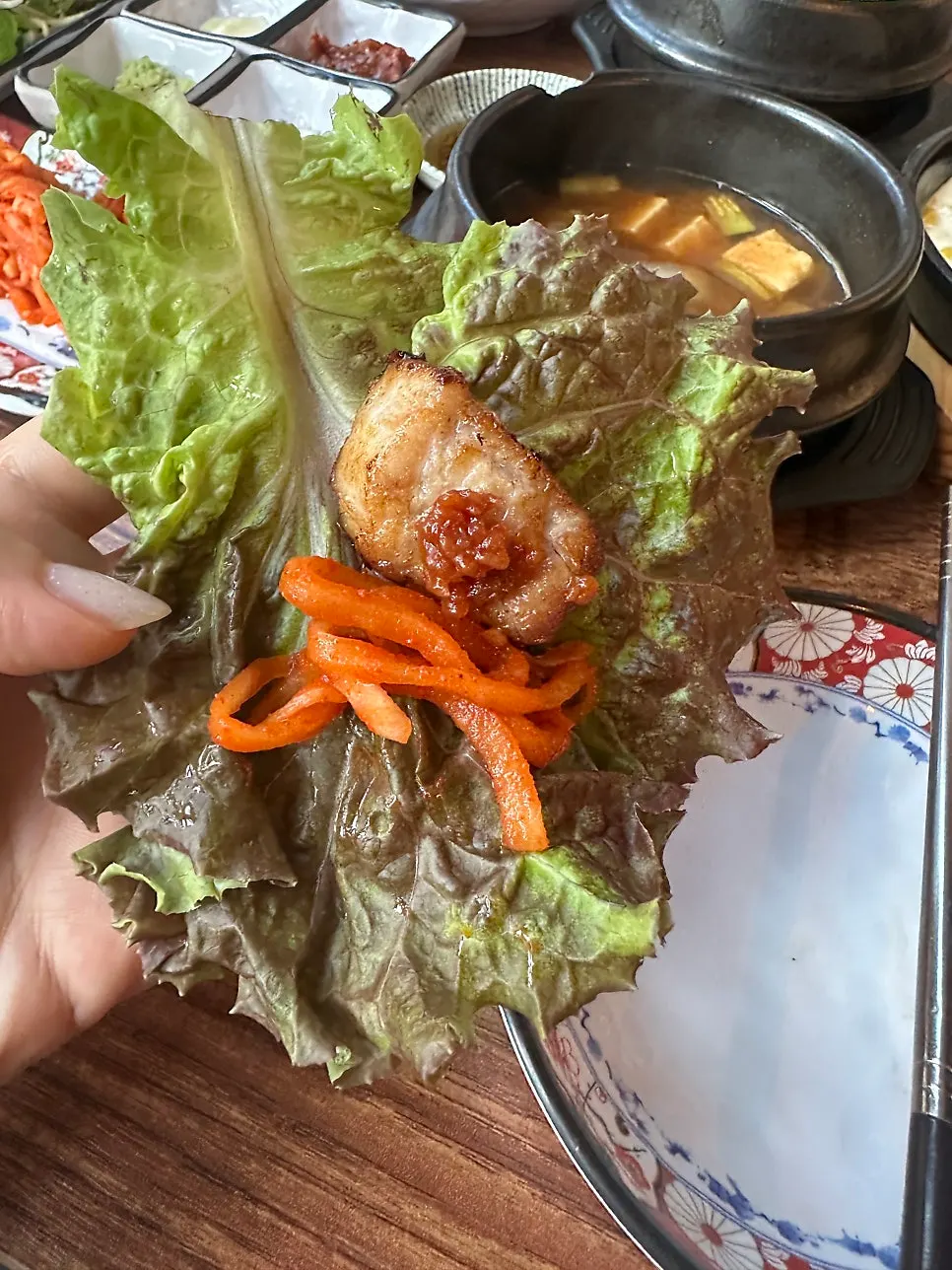 Thick samgyeopsal and shredded green onion on a lettuce wrap