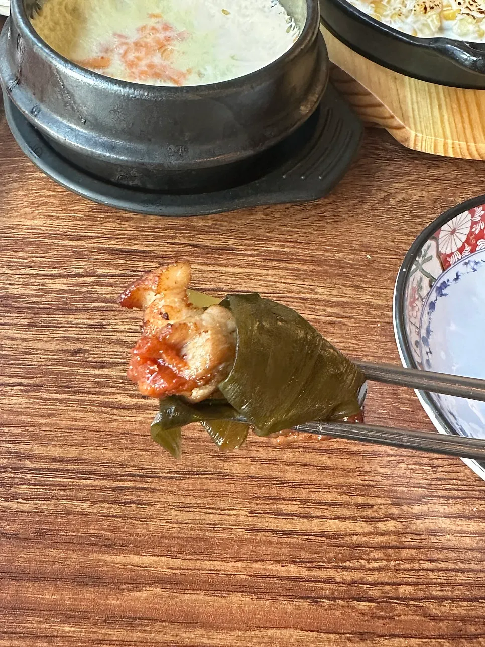 Preparing a bite of samgyeopsal lettuce wrap