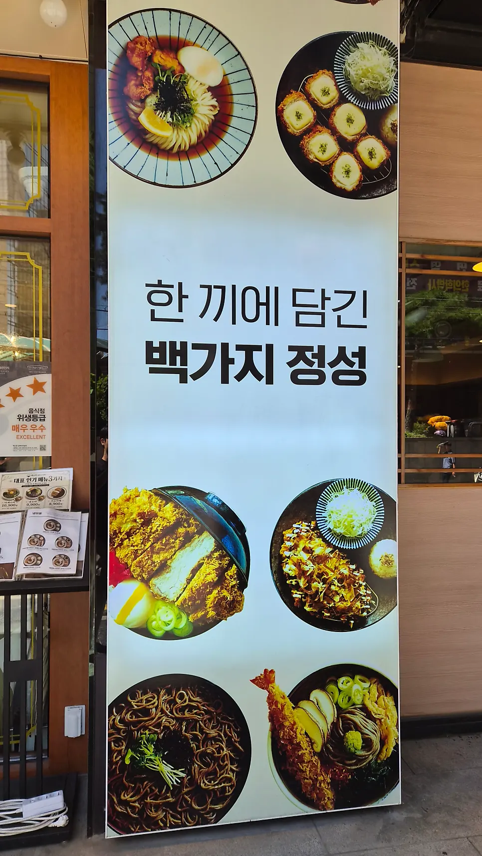 Entrance promotional panel showing noodle dishes and tonkatsu