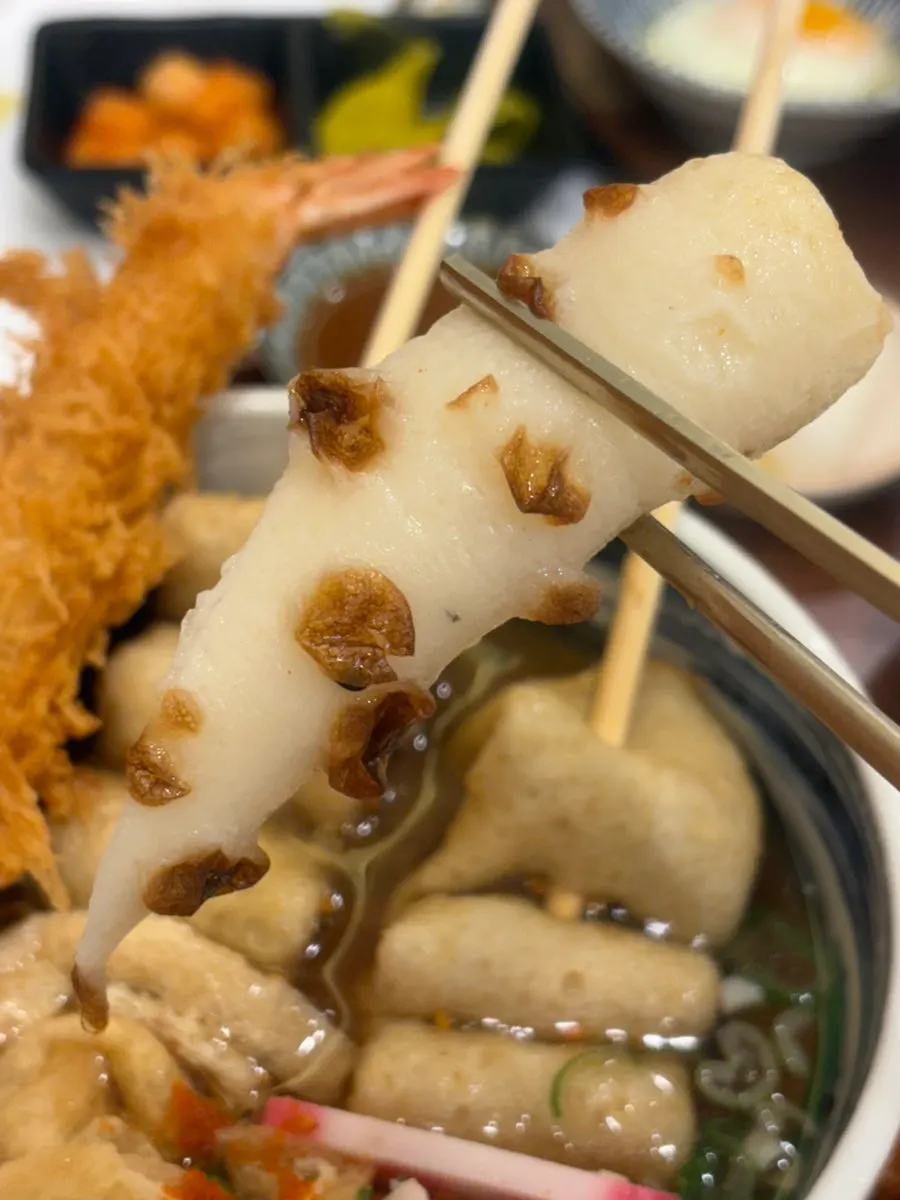 Chewy udon noodles lifted with chopsticks