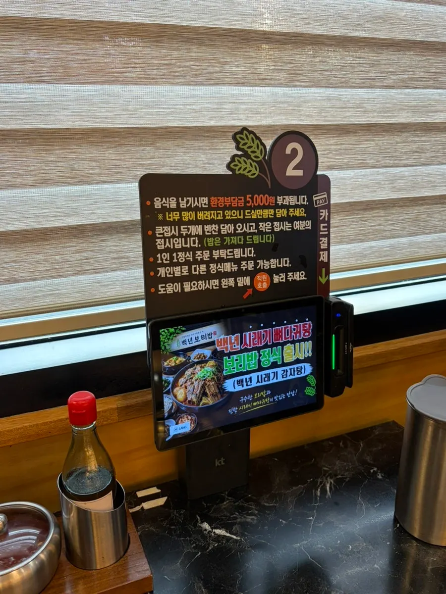 Wall with Korean food imagery and tables at Baengnyeon Boribap