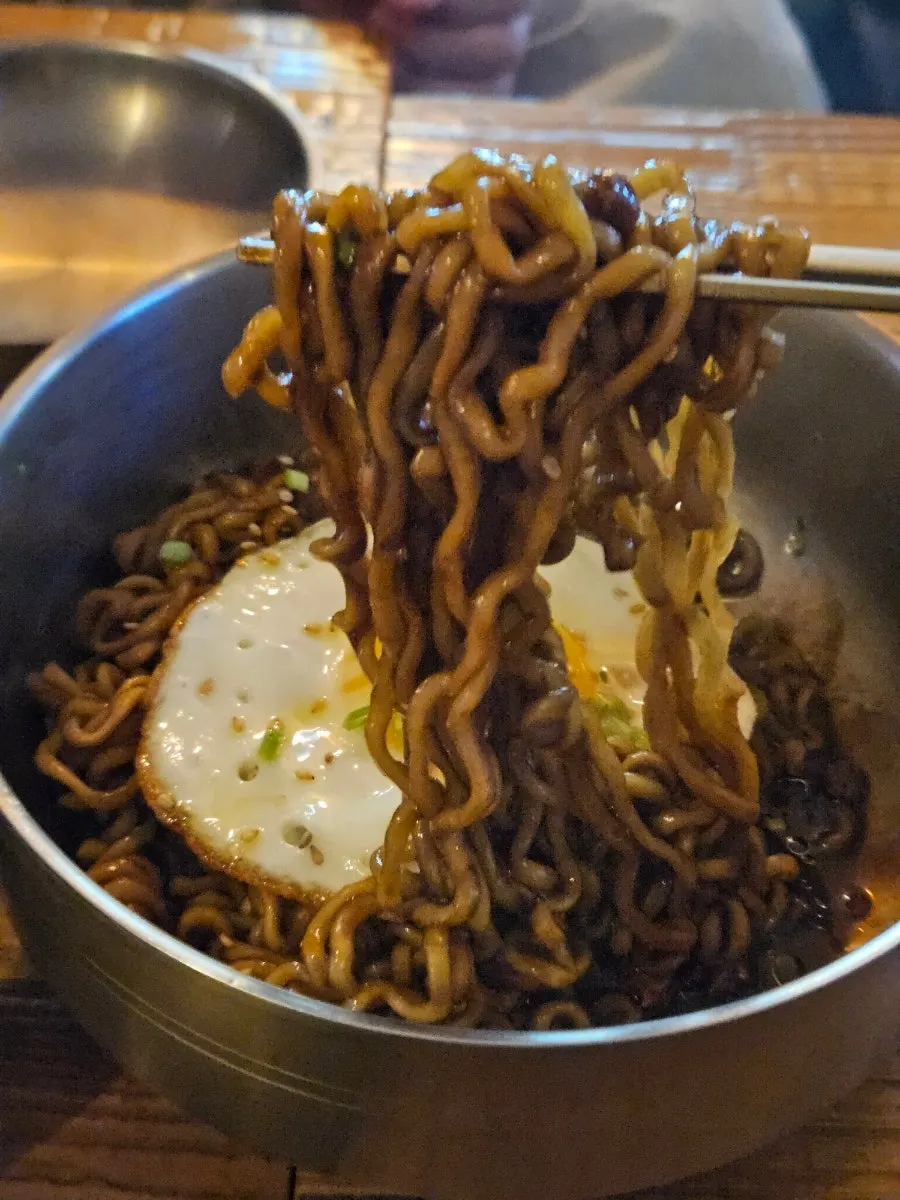 Truffle jjapaghetti noodles lifted with sauce clinging to them