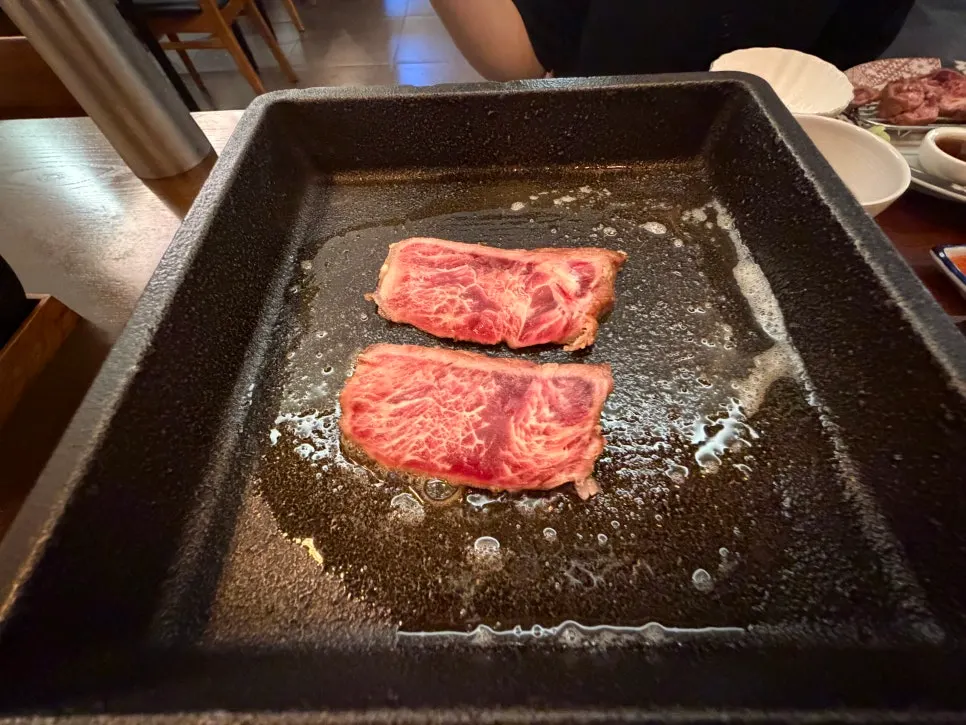 Two slices of sirloin with melted butter on a personal tabletop grill
