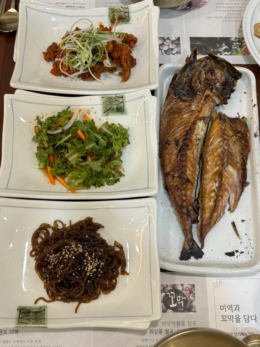 Table with stir-fried pork, japchae, and grilled mackerel