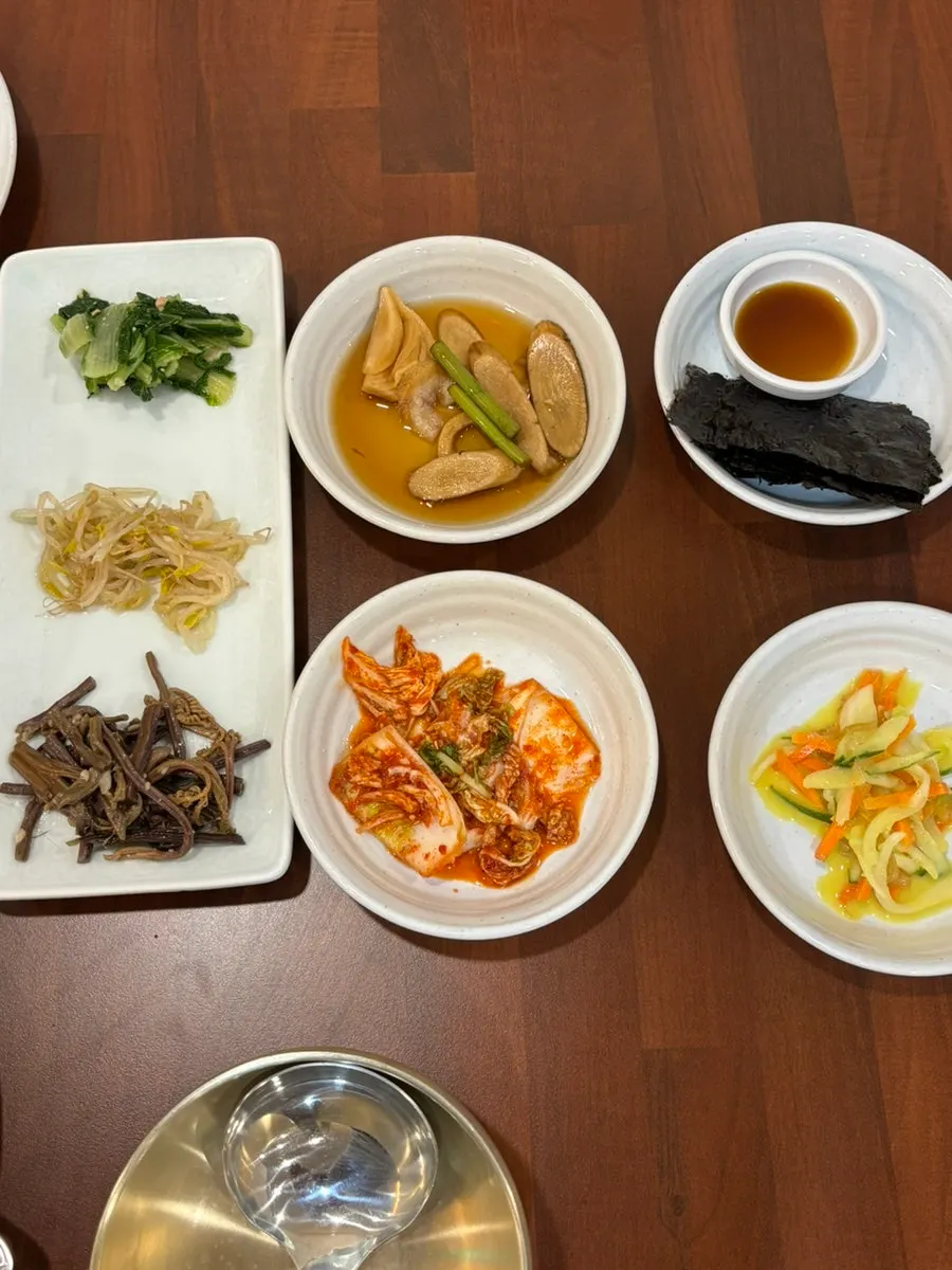 Side dishes of pickled radish, kimchi, seaweed, and mustard salad