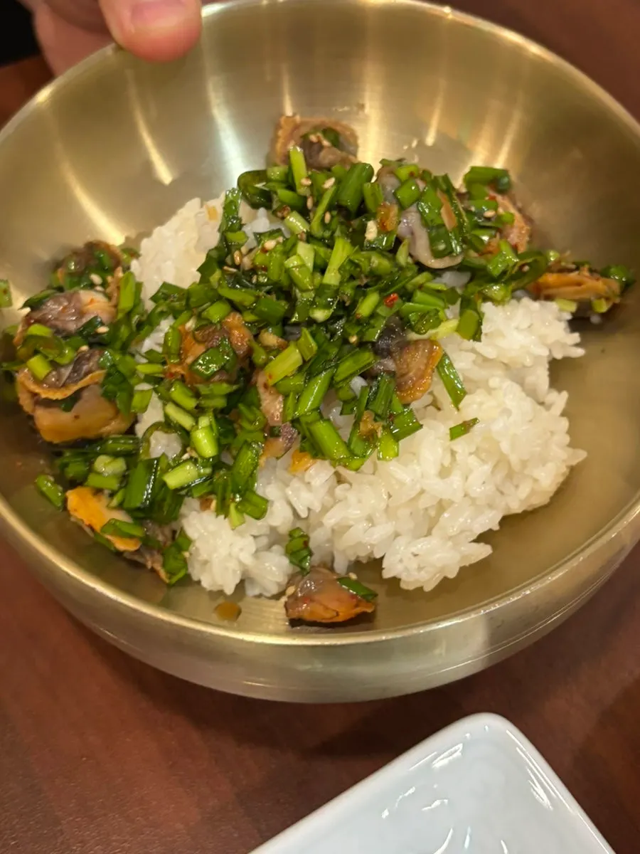 A spoonful of rice topped with cockle bibim