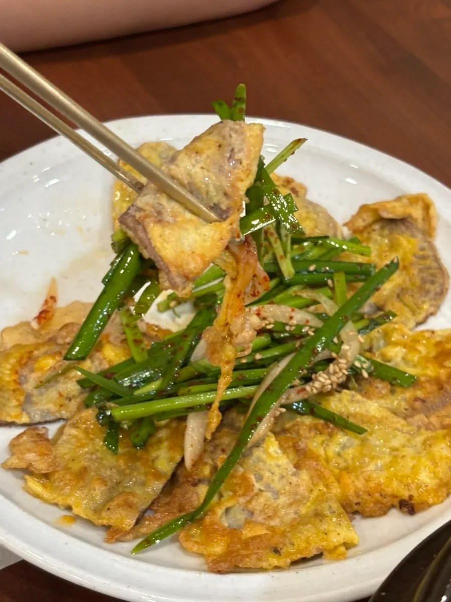 A piece of beef jeon topped with chive salad