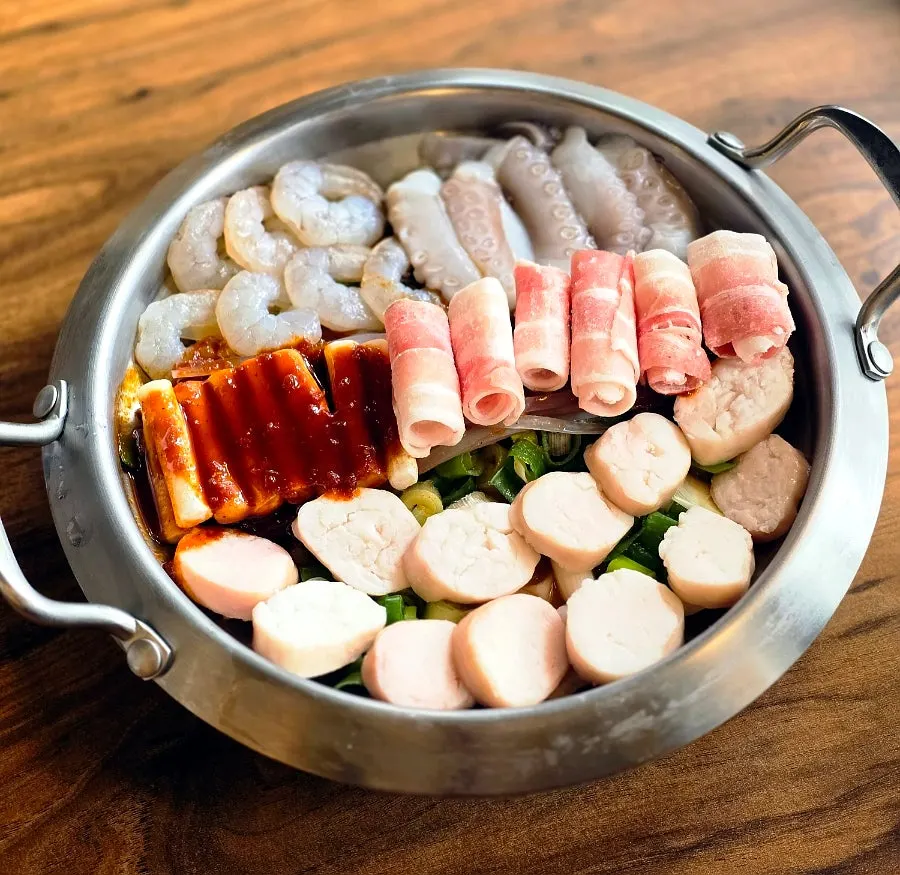 Side dishes of white kimchi, pickled radish, and perilla leaves