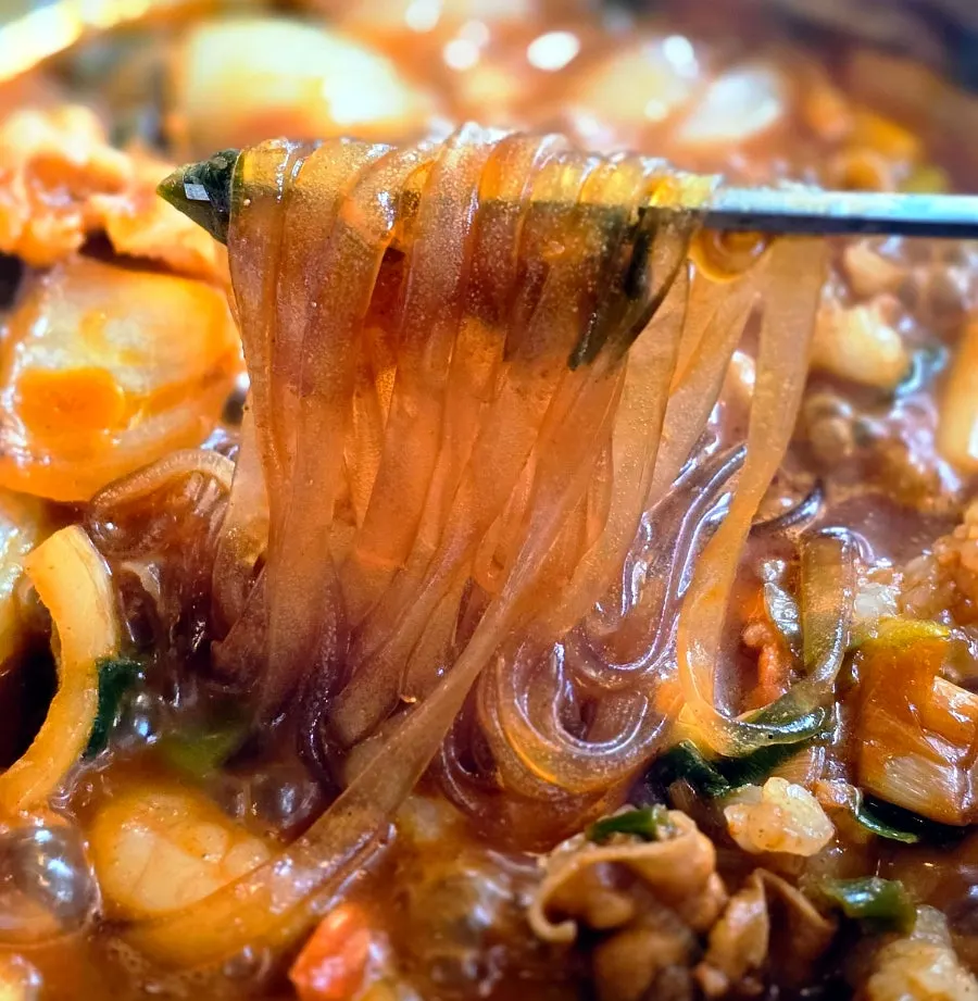 Spoonful of nakgopsae broth lifted from the pot