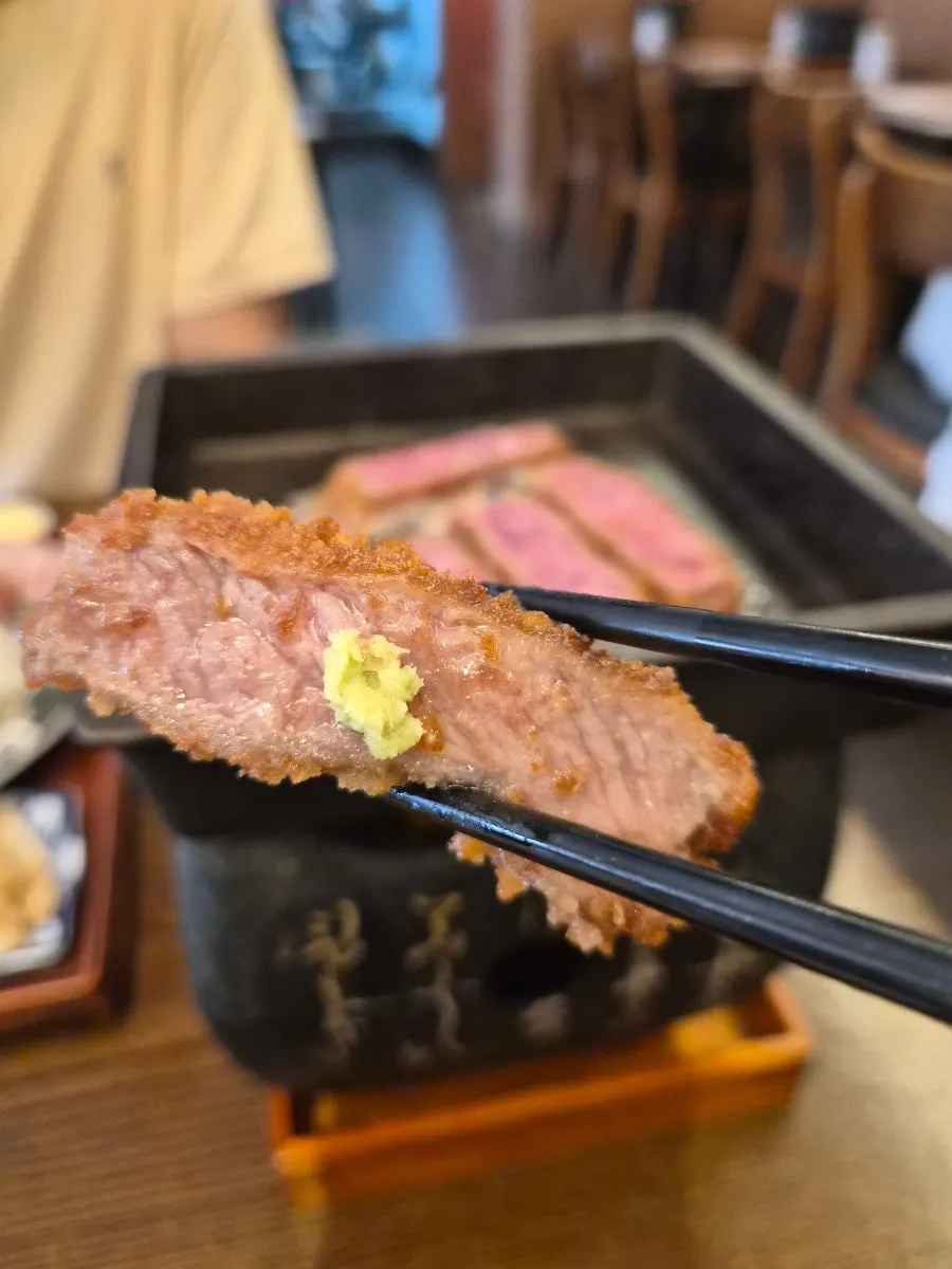 Two pieces of gyukatsu grilling on the mini brazier