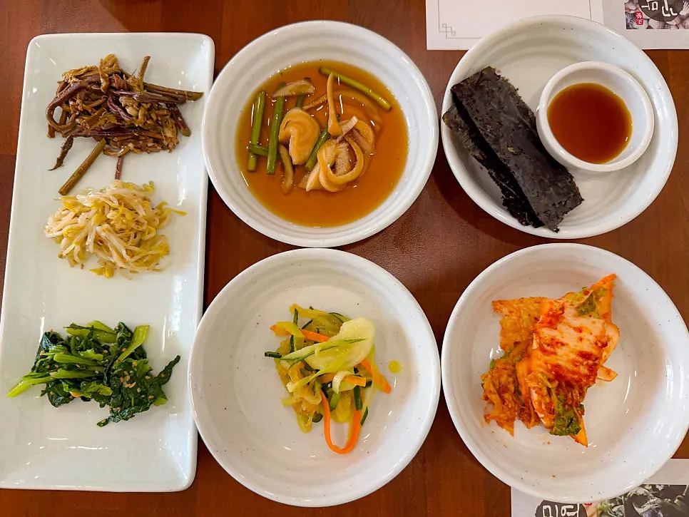 Pickled vegetables, jellyfish salad, seaweed, and fresh kimchi side dishes