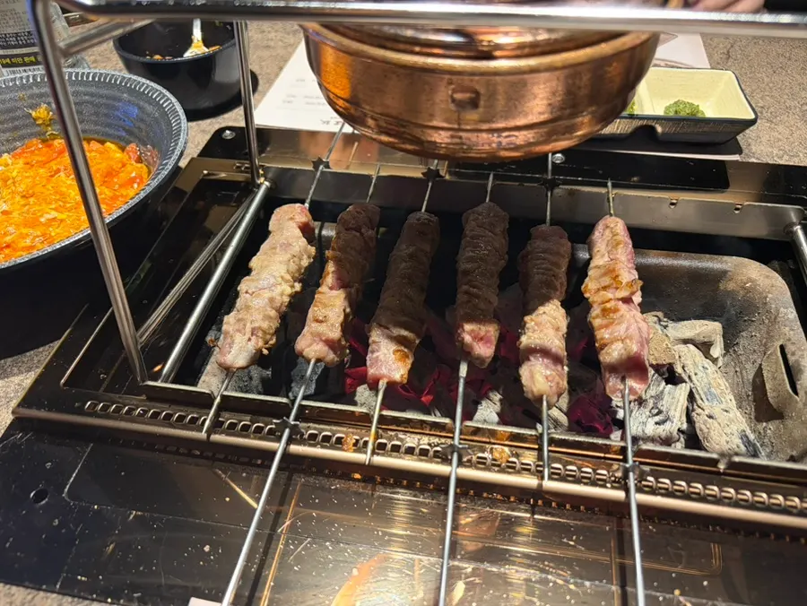 Pre-grilled lamb skewers finishing on the tabletop grill