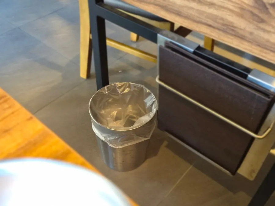 A small trash bin placed at every table