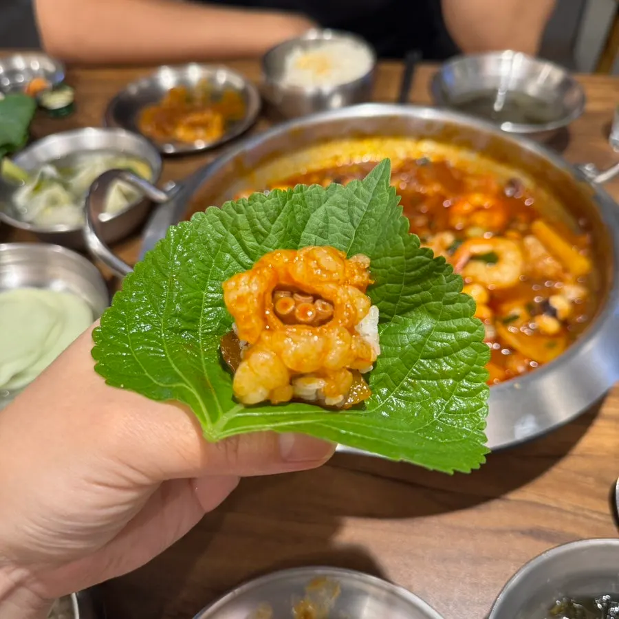 A bite of perilla leaf wrapped nakgopsae with mayonnaise