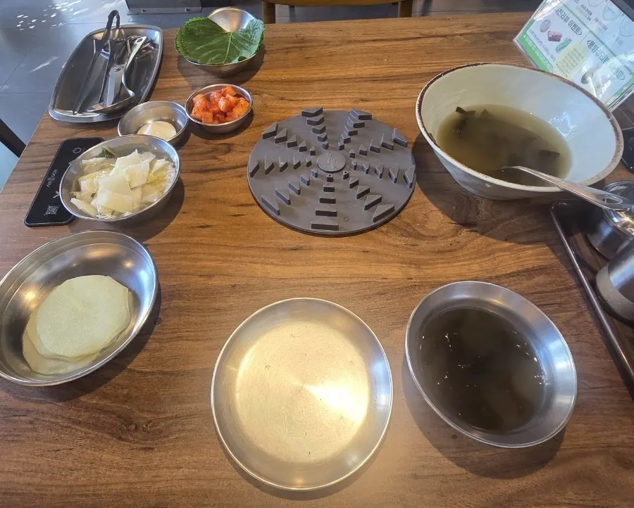 Table set with side dishes including white kimchi and seaweed soup
