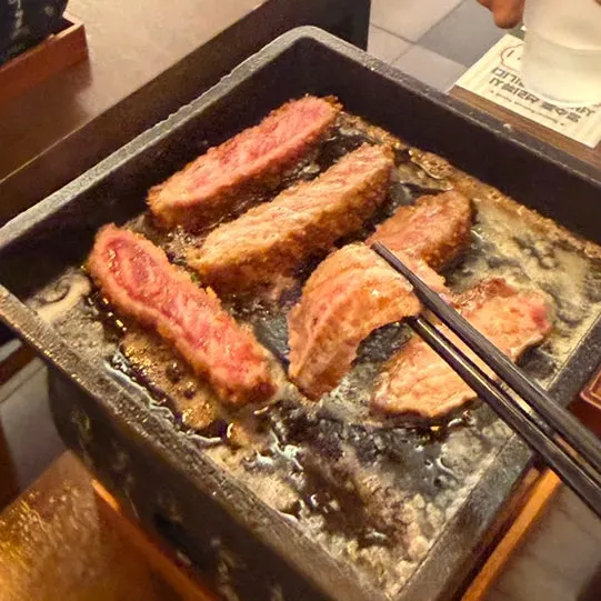Sirloin steak grilling on a brazier