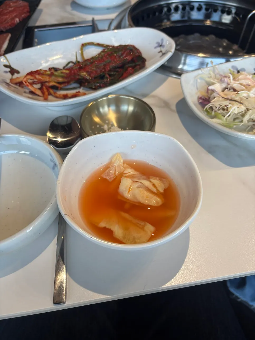 Table setting with green onion kimchi and water kimchi
