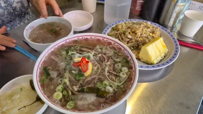Brisket pho, pineapple fried rice, and wingbong laid out together