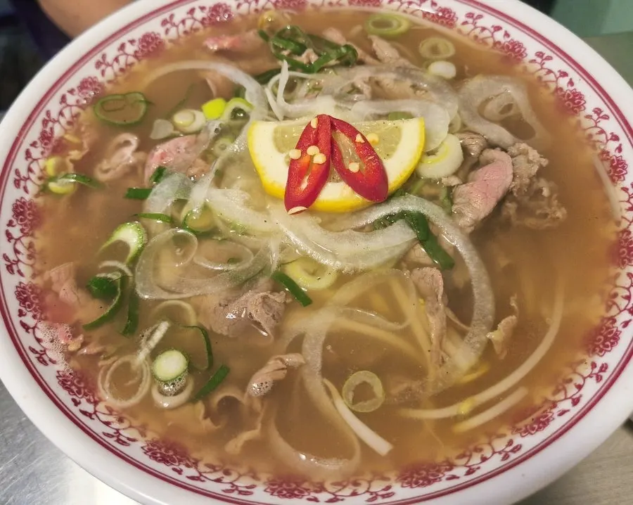 A spread of rare beef pho, bun cha and side dishes