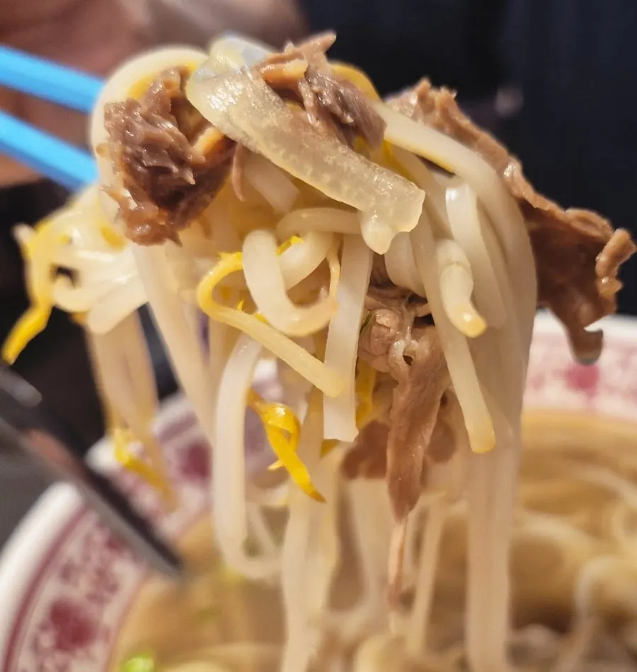 Close-up of pho piled high with rare beef tenderloin