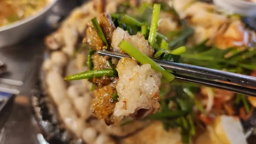 A piece of gopchang dipped in sauce