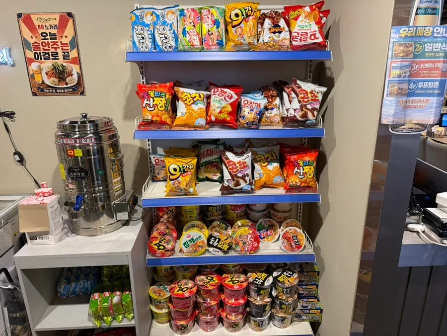 Snack bar shelves stocked with chips and cup ramyeon good for pairing with drinks